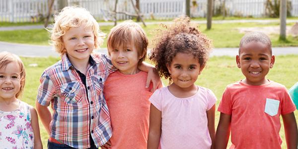 Group of young children holding hands outside.